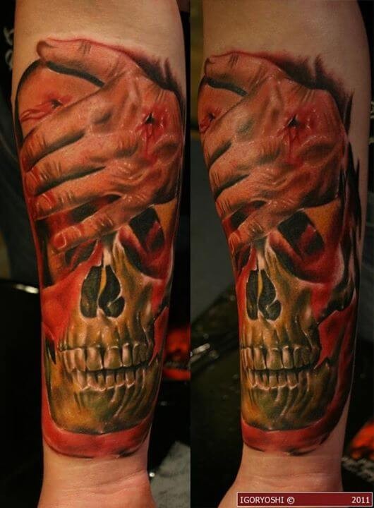 Realistic looking colored forearm tattoo of human skull with wounded hand