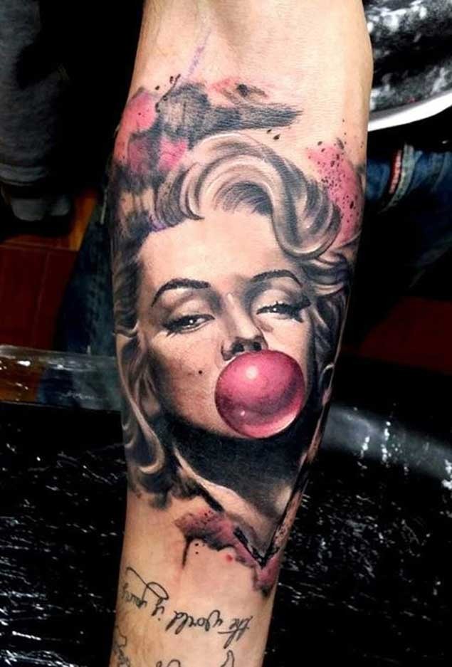 Realistic looking colored Merlin Monroe with gum balloon tattoo on forearm