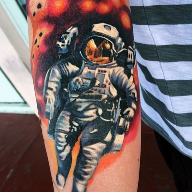 Tatuaje en el antebrazo, astronauta realista en el fondo rojo
