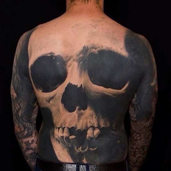 Realistic looking colored whole back tattoo of old human skull