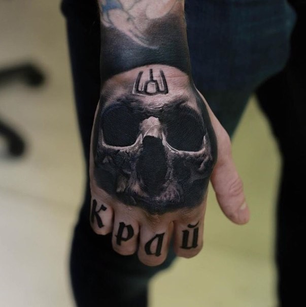 Realistic looking detailed hand tattoo of human skull with lettering