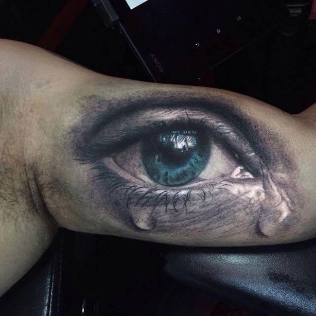 Realistic tearing blue eye tattoo on arm by Darwin Enriquez