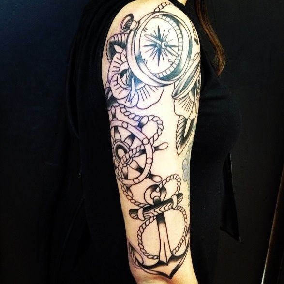Tatuaje  de ancla con cuerda, compás y rosas en el brazo