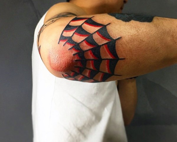 Red and black ink half of spiderweb tattoo on elbow in old school style
