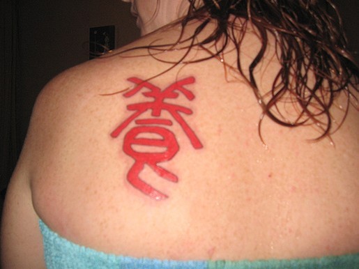 Red chinese character tattoo on scapula