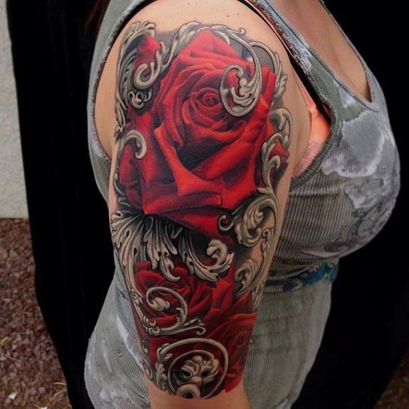 Detailed red roses with ornamental tattoo on arm