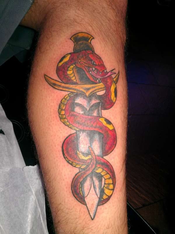 Red snake on dagger tattoo on leg