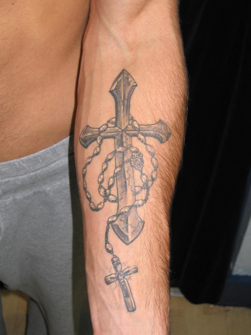 Religious gray-ink cross with beads tattoo on forearm