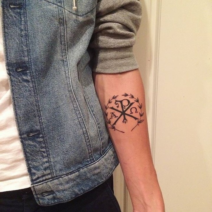 Tatuaje en el antebrazo,
monograma Chi Rho y corona de laurel, tinta negra