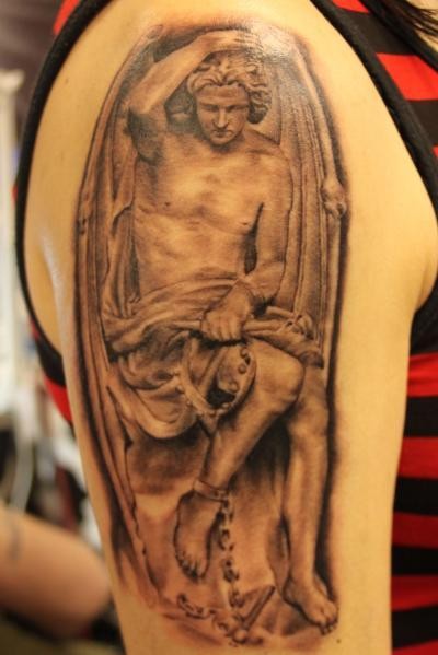 Tatuaje en el brazo, ángel con cadena en la pierna