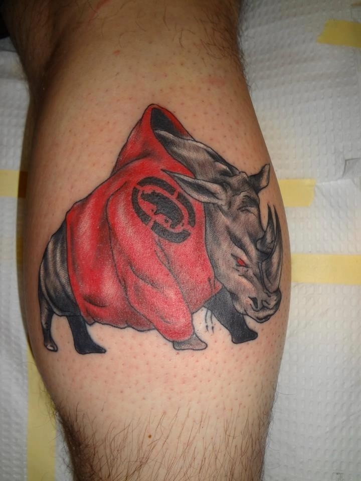 Tatuaje en la pierna,
rinoceronte peligroso en el traje rojo