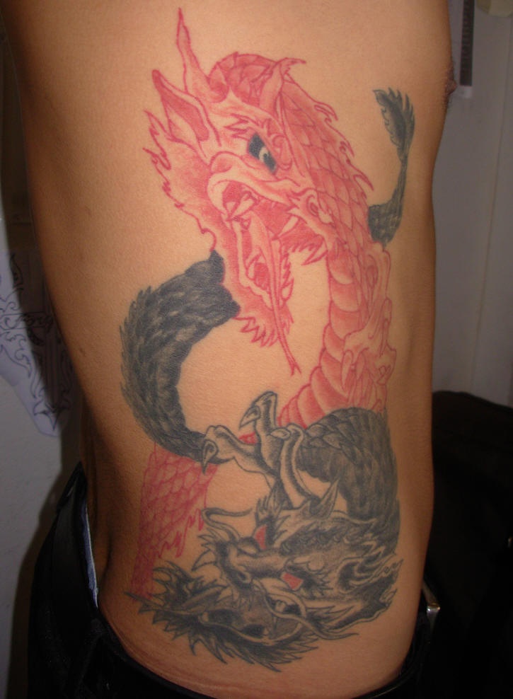 Rib tattoo, two red and black crossed dragons