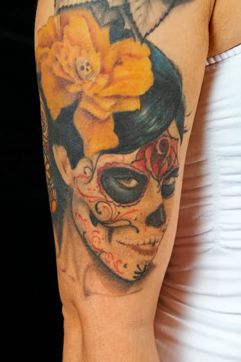 Tatuaje en el brazo, la santa muerte con la flor amarilla
