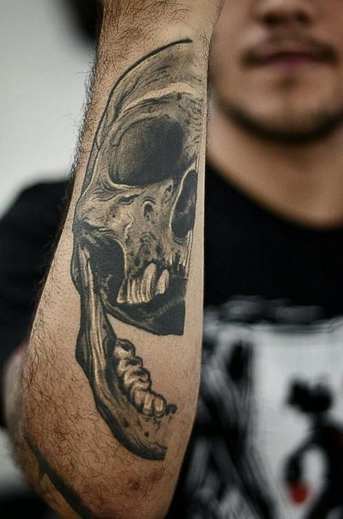 Scary gray-ink half skull tattoo on outer forearm