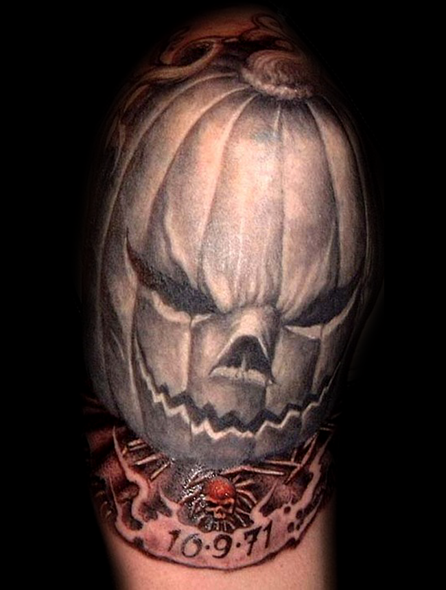 Scary Halloween pumpkin and memorial date on banner shoulder tattoo with tiny skull