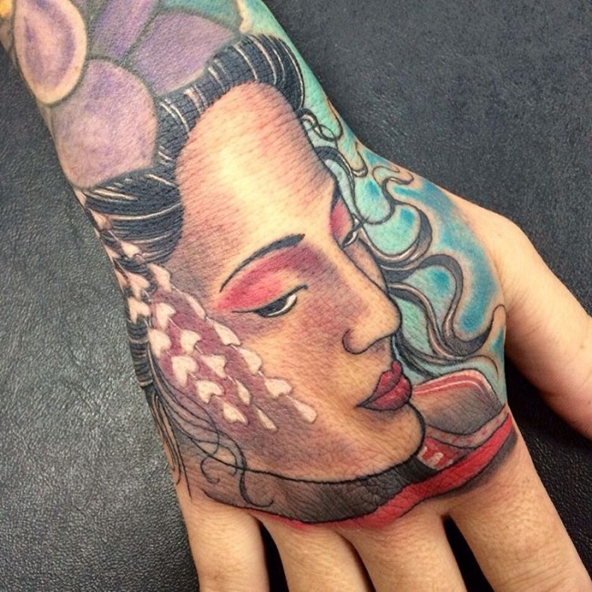 Sensitive Asian traditionally colored Geisha's portrait tattoo on hand