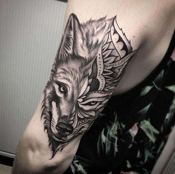 Tatuaje del brazo diseñado original y separado del rostro de lobo estilizado con adornos