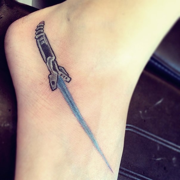 Sharp pale blue detailed light saber tattoo on foot