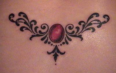 Shipshape tribal tattoo with red gemstone