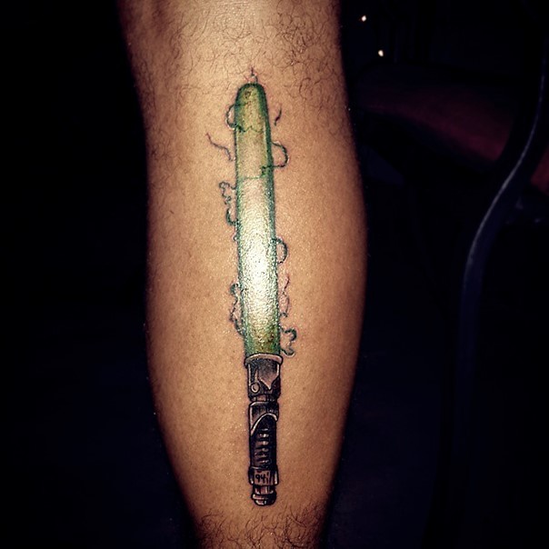 Simple 3D like little leg tattoo of green lightsaber