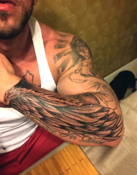 Simple black ink detailed wing with lettering tattoo on arm