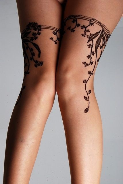 Simple black ink floral tattoo on legs