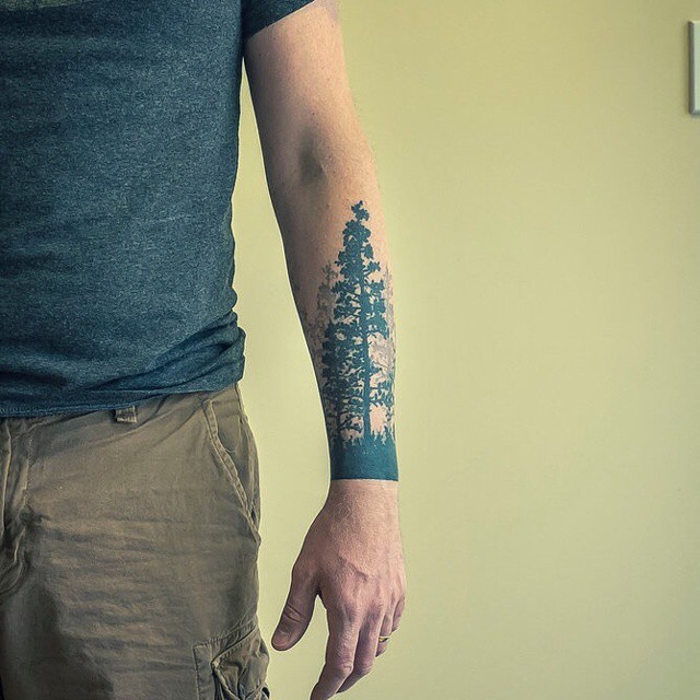 Simple black ink forearm tattoo of dark deep forest