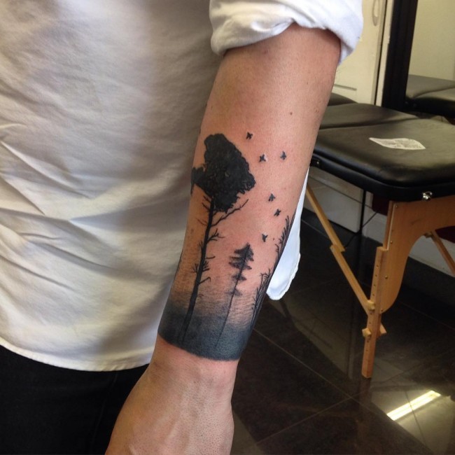 Simple black ink forearm tattoo of forest with birds