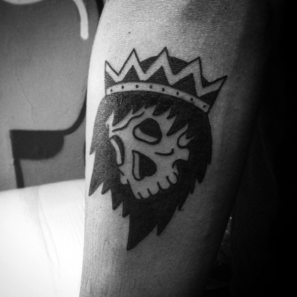 Simple black ink human skull with crown tattoo on forearm