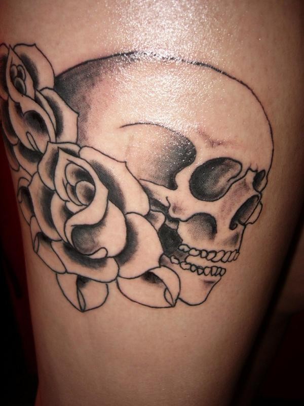 Simple black ink human skull  with roses tattoo on thigh