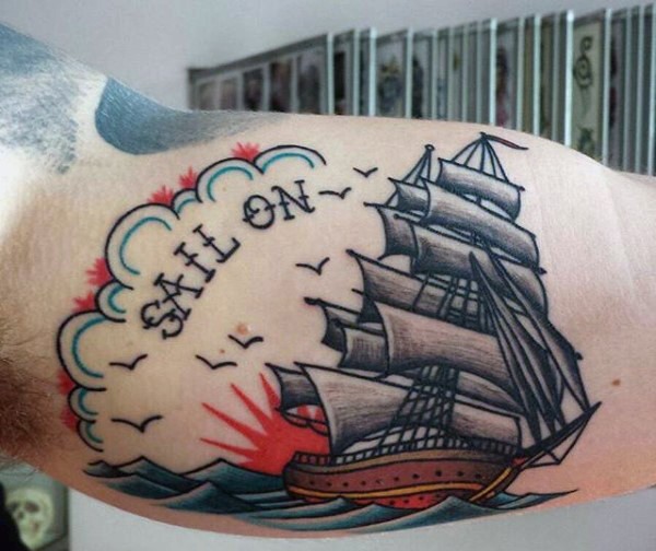Simple cartoon like multicolored ship with letting tattoo on biceps
