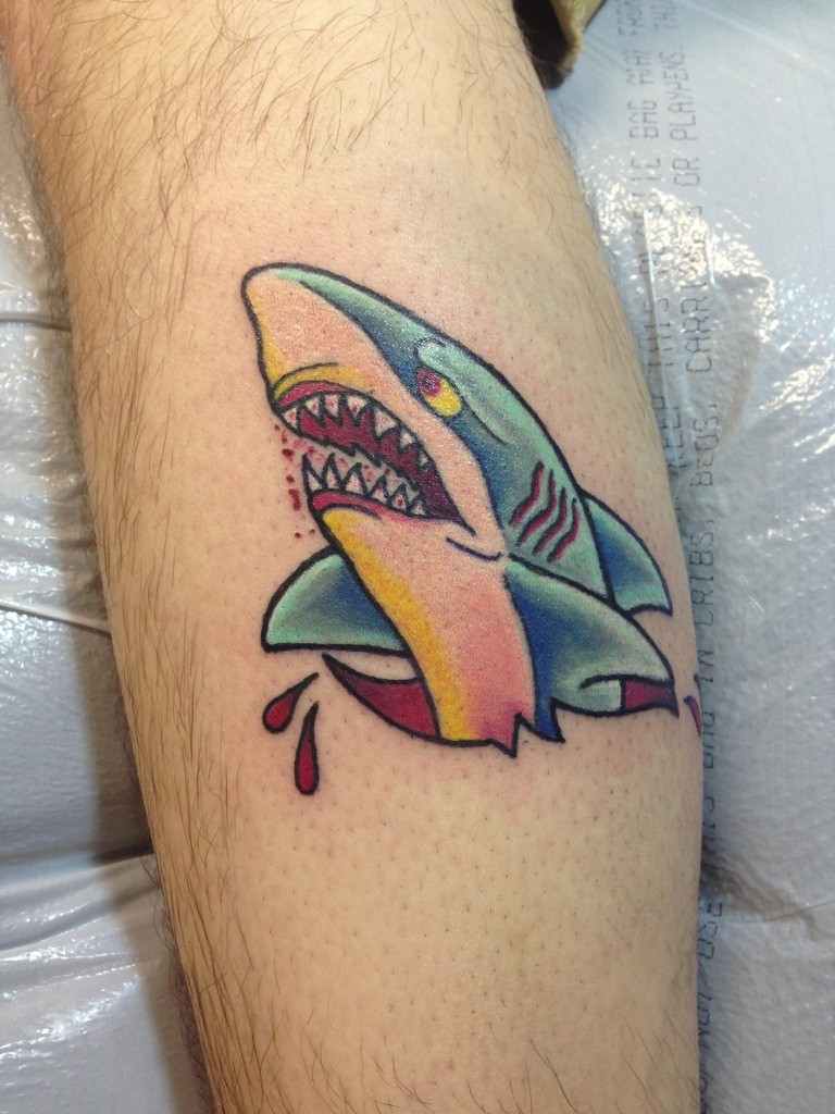 Simple colored and painted little shark tattoo on leg