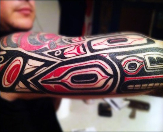 Tatuaje en el brazo, ornamento tribal multicolor fascinante