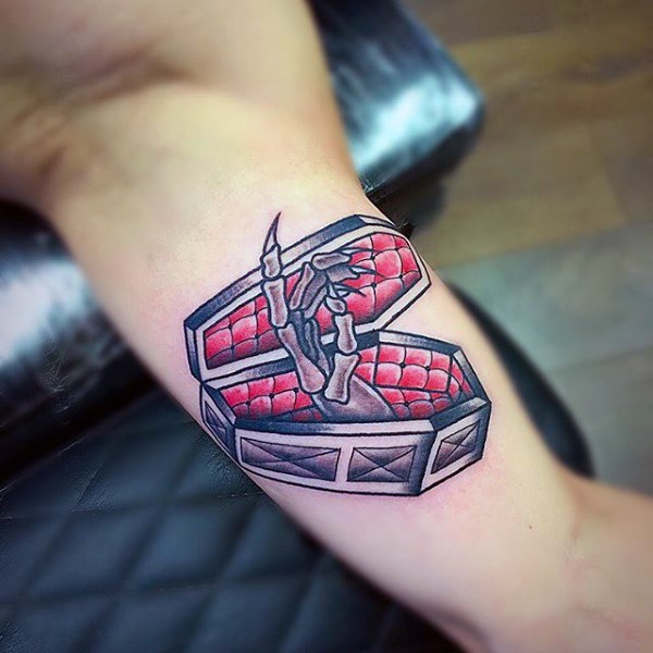Simple colored little coffin whit skeleton hand tattoo on biceps