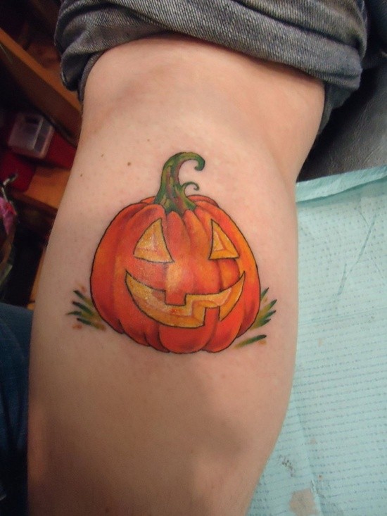 Simple designed and colored little Halloween pumpkin tattoo on leg