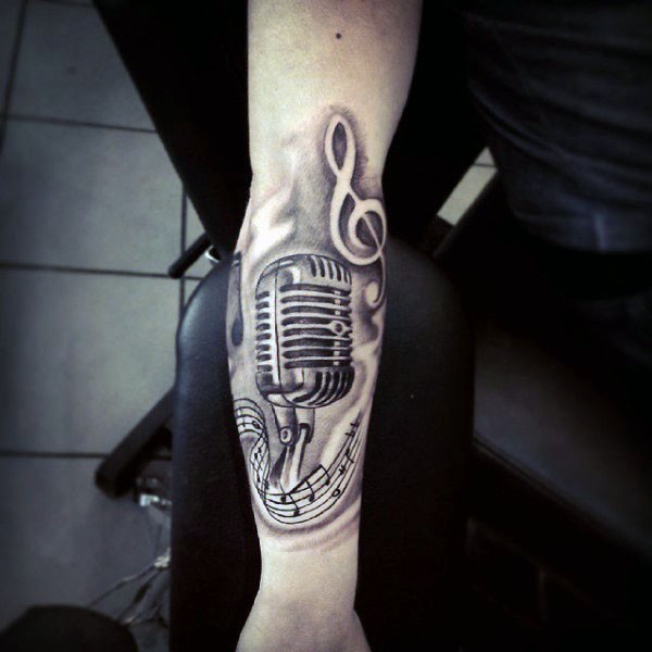 Tatuaje en el antebrazo, micrófono retro con notas y clave de sol
