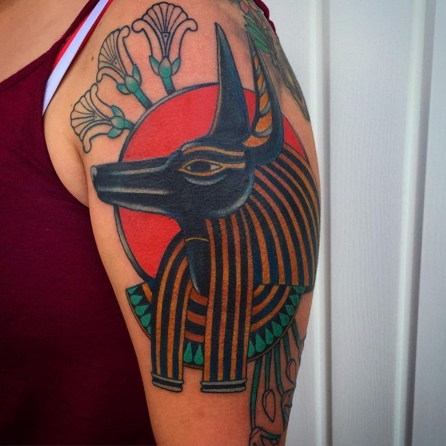 Tatuaje en el brazo,
dios egipcio con sol y flores