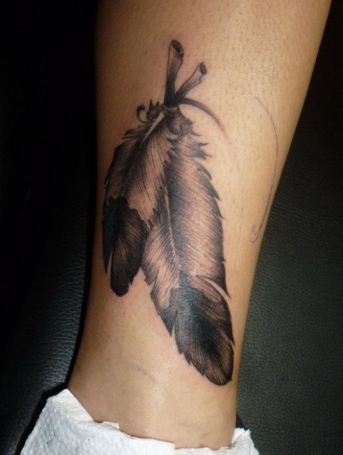 Simple gray-ink eagle feather tattoo on shin