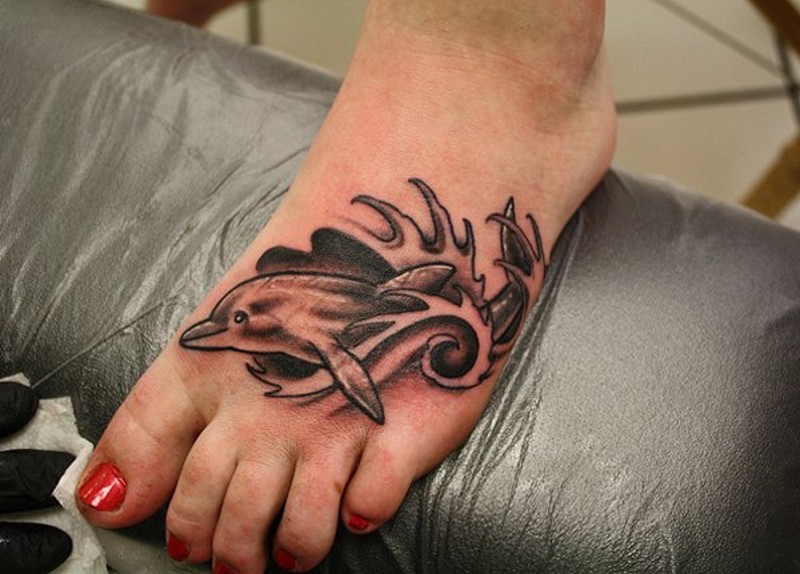 Tatuaje en el pie, delfín en olas, diseño sencillo gris