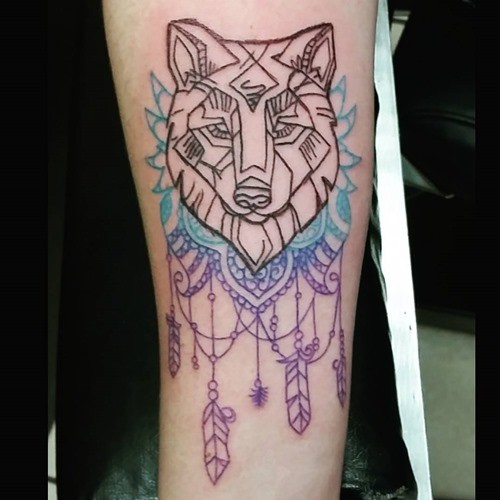 Simple homemade like carelessly drawn wolf tattoo on forearm with feather