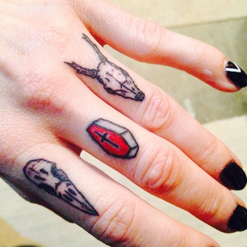 Simple homemade like colored tiny animal skulls tattoo on fingers with coffin