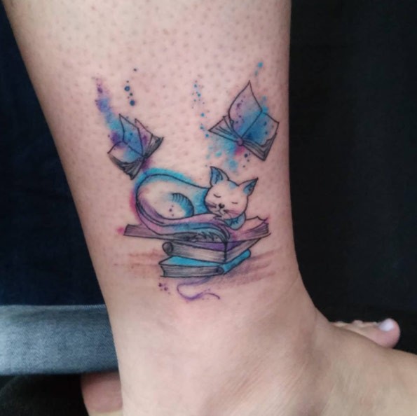 Simple homemade like watercolor like sleeping cat with books tattoo on ankle