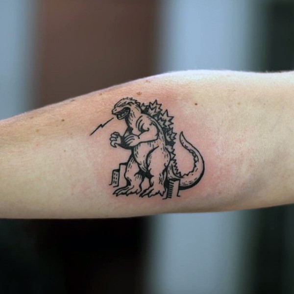 Tatuaje en el antebrazo,
Godzilla pequeña simple, tinta negra