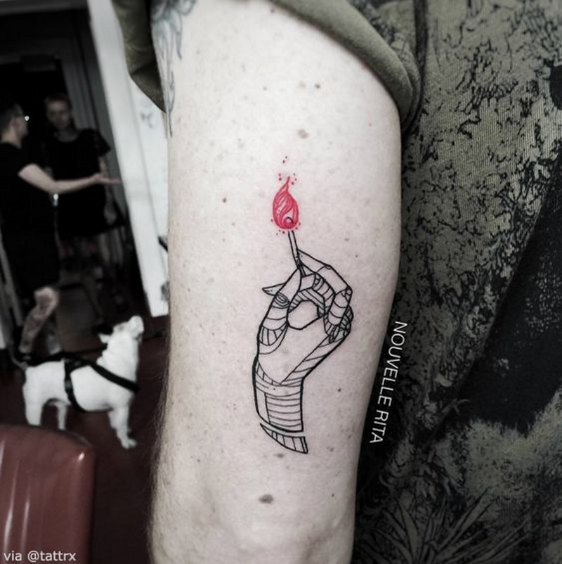 Tatuaje en el brazo, mano que lleva cerilla