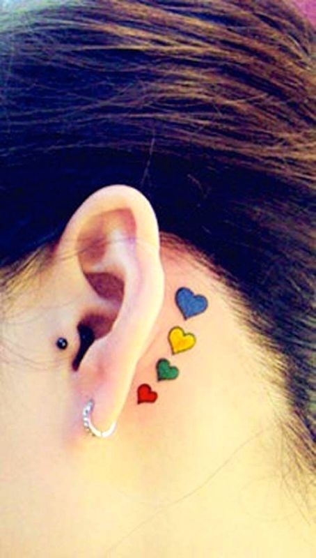 Tatuaje detrás de la oreja, corazoncitos diminutos de varios colores