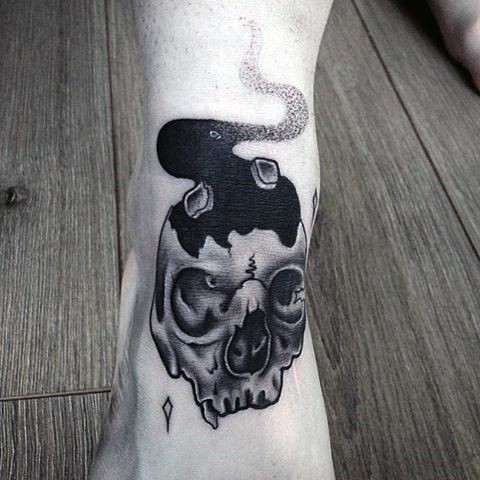 Simple painted little black ink skull tattoo on leg