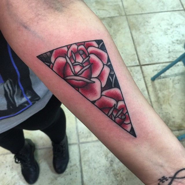 Simple triangle shaped tattoo on forearm stylized with red roses