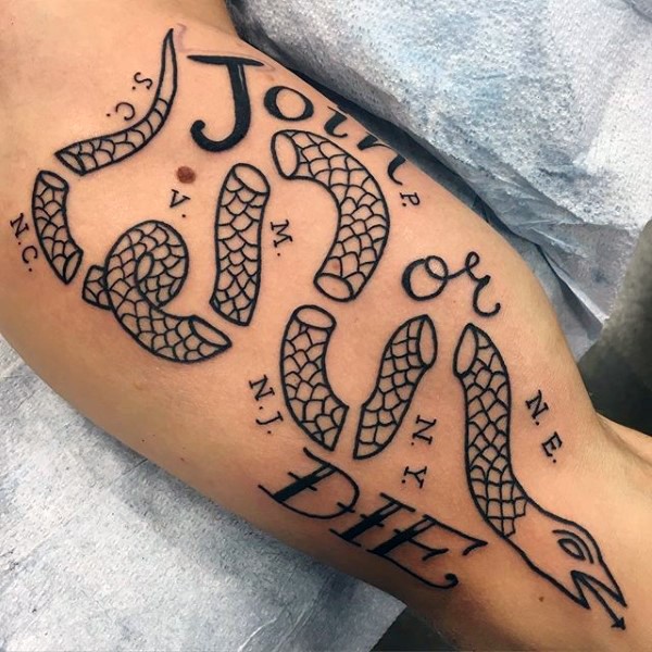 Simple typical black ink biceps tattoo of ripped snake with lettering