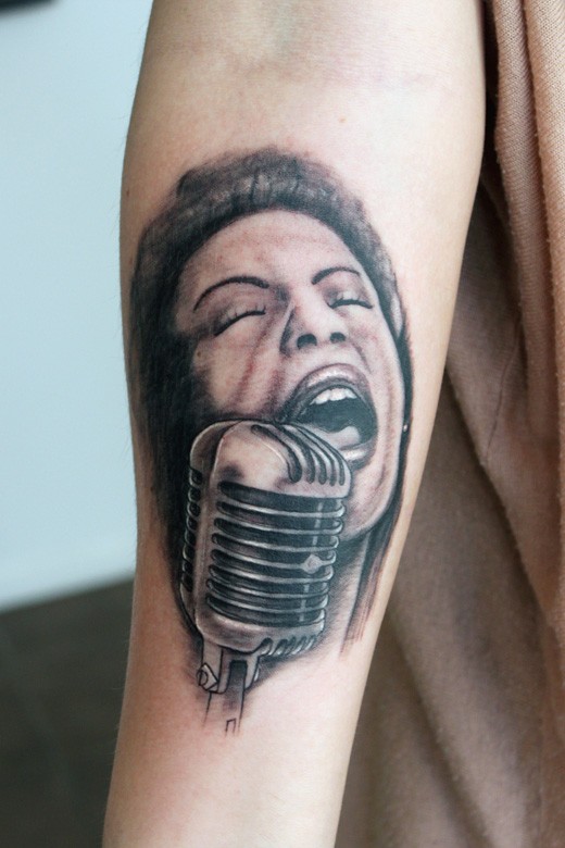 Singing lady and old microphone black and white portrait tattoo on forearm in realism style