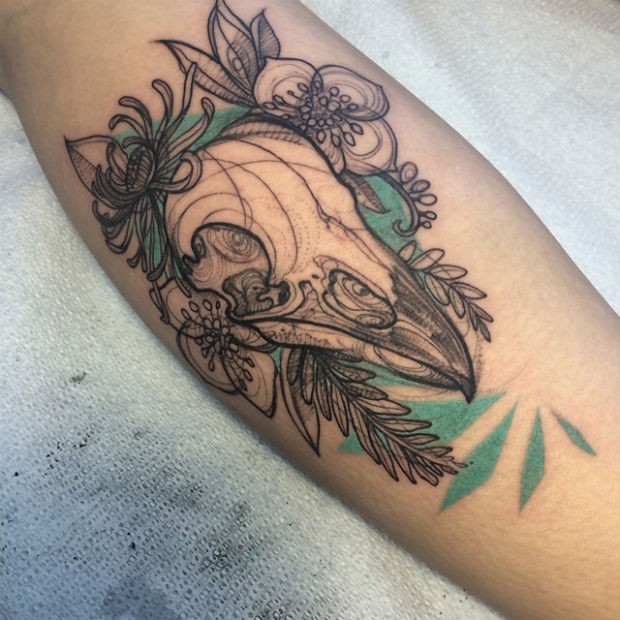 Sketch style colored arm tattoo of birds skull with flowers